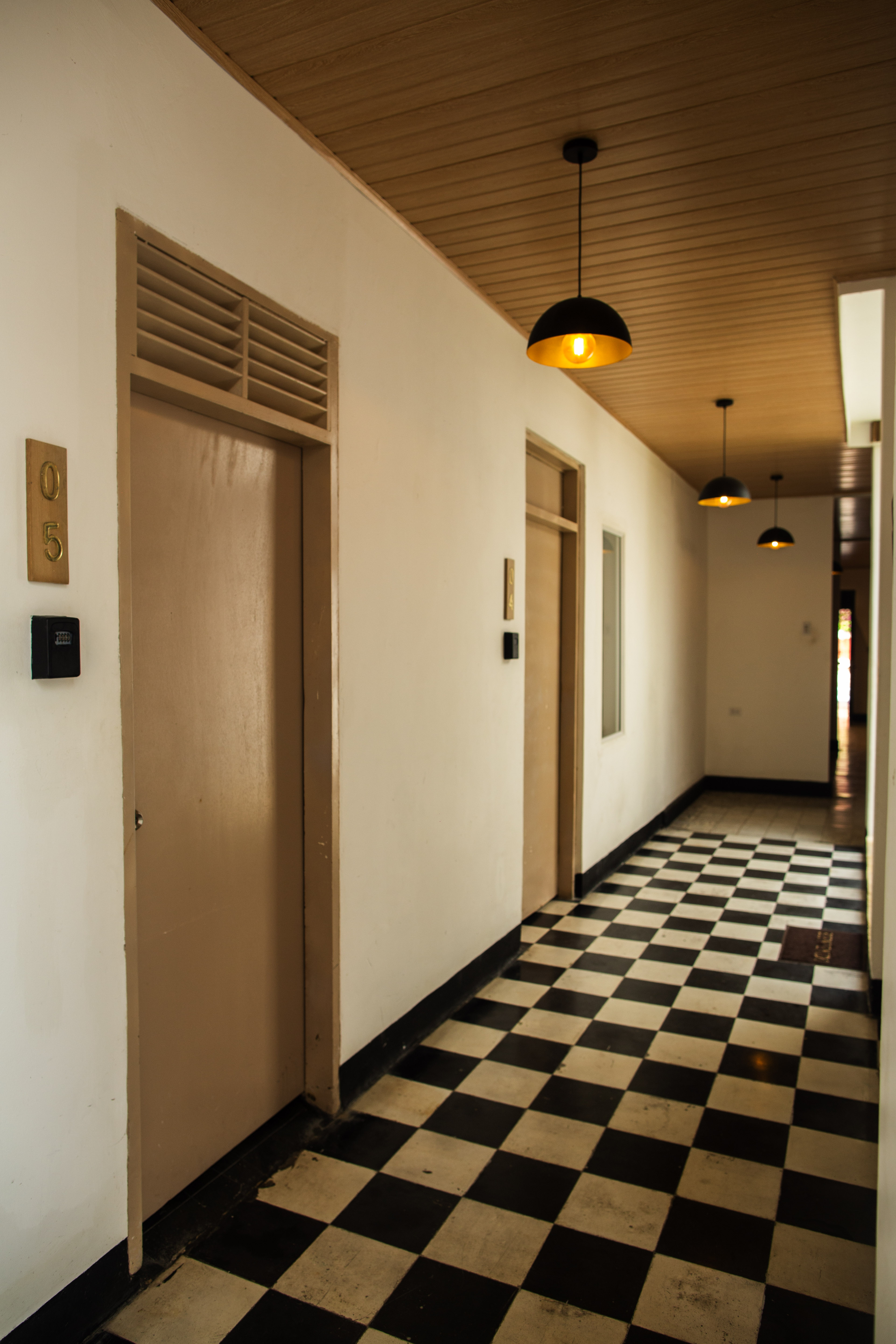 Pasillo con piso ajedrezado y luz natural del hotel boutique